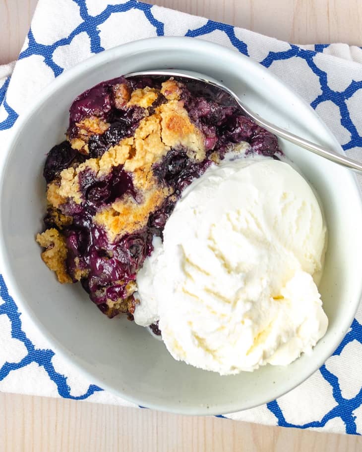 Blueberry Dump Cake baking dish, bowl with one piece cut out with vanilla ice cream