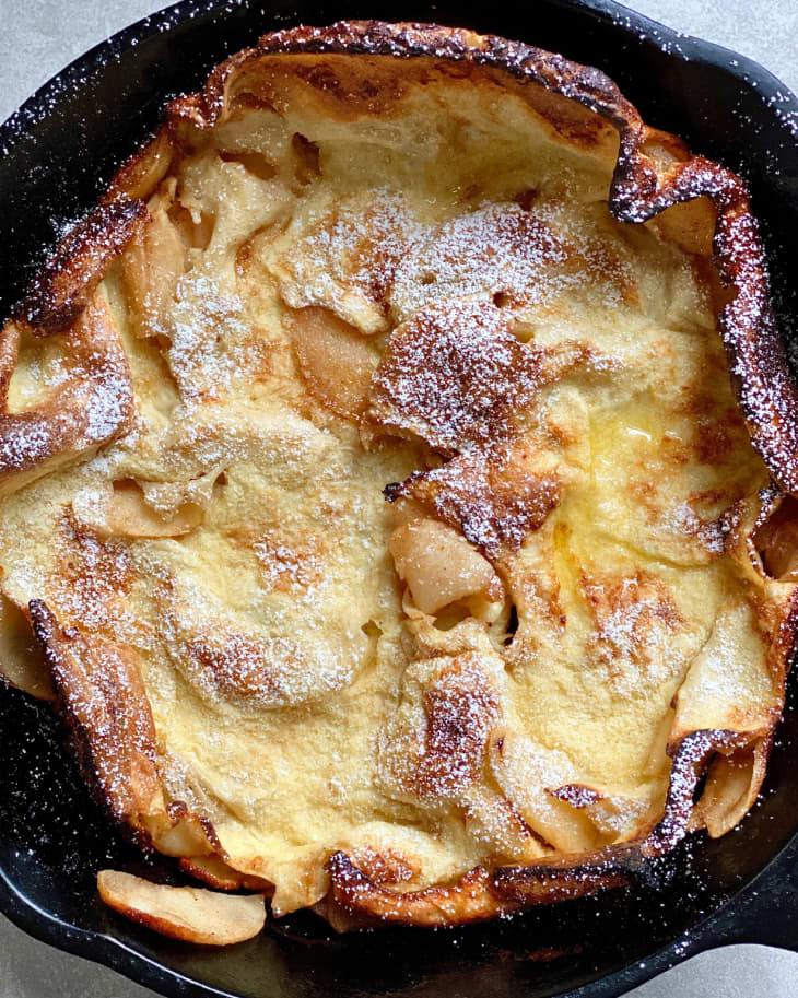 fluffy light german pancake in cast iron skillet with browned edges and curly ends