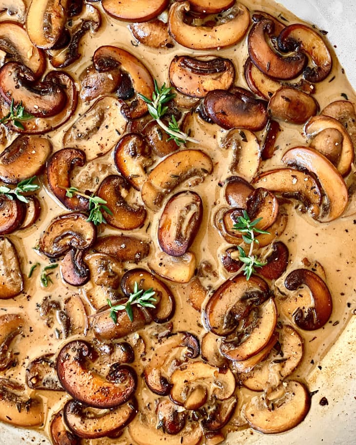 mushrooms in cream sauce in skillet with thyme garnish
