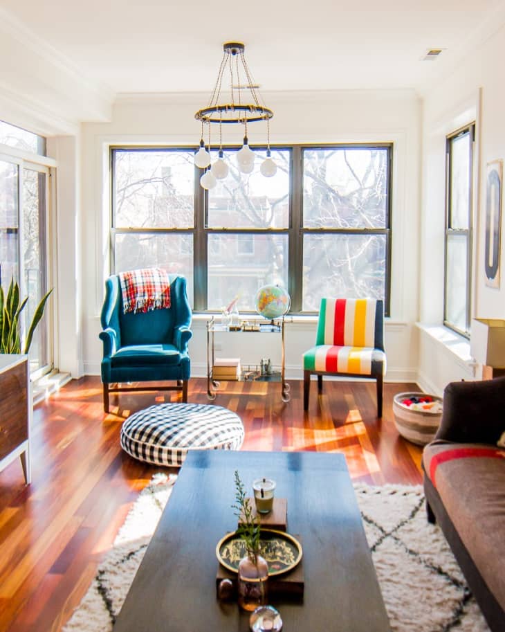 Bright living room with blue and striped chairs, large windows, globe on a cart, and a wooden coffee table with decor.