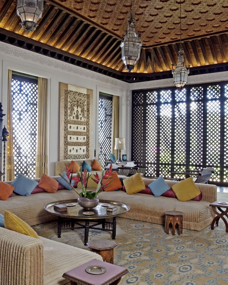 Luxurious living room with ornate ceiling, patterned rug, large sectional sofa, colorful cushions, and decorative lanterns.