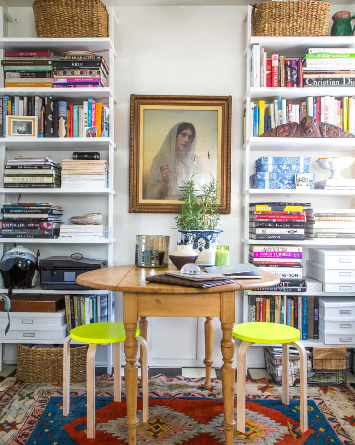 A painting between two bookshelves with a kitchen table in the foreground.
