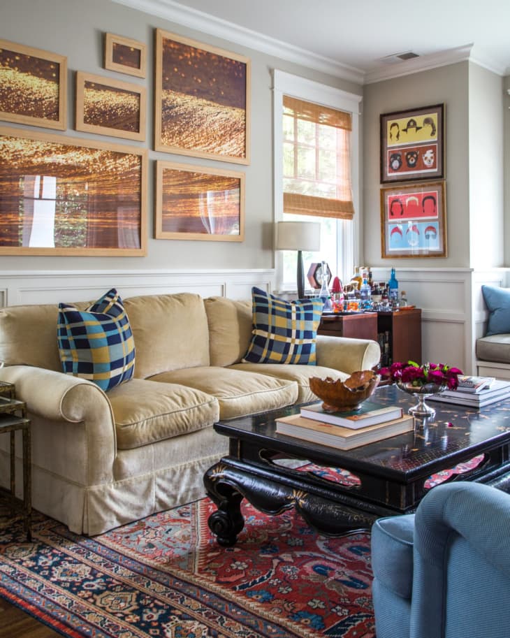 Living room with beige sofa, blue plaid pillows, black coffee table, and framed art on walls.
