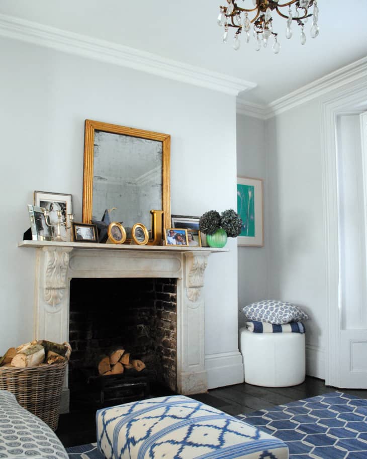 Living room with a white fireplace, gold mirror, blue patterned rug, and chandelier.