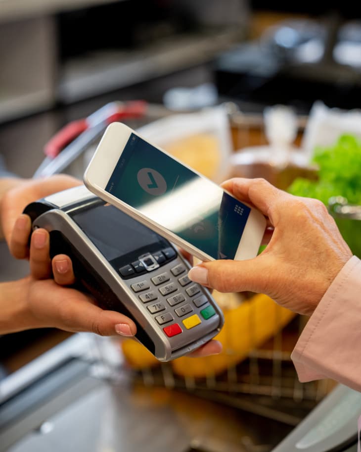Unrecognizable female customer paying for groceries with smartphone