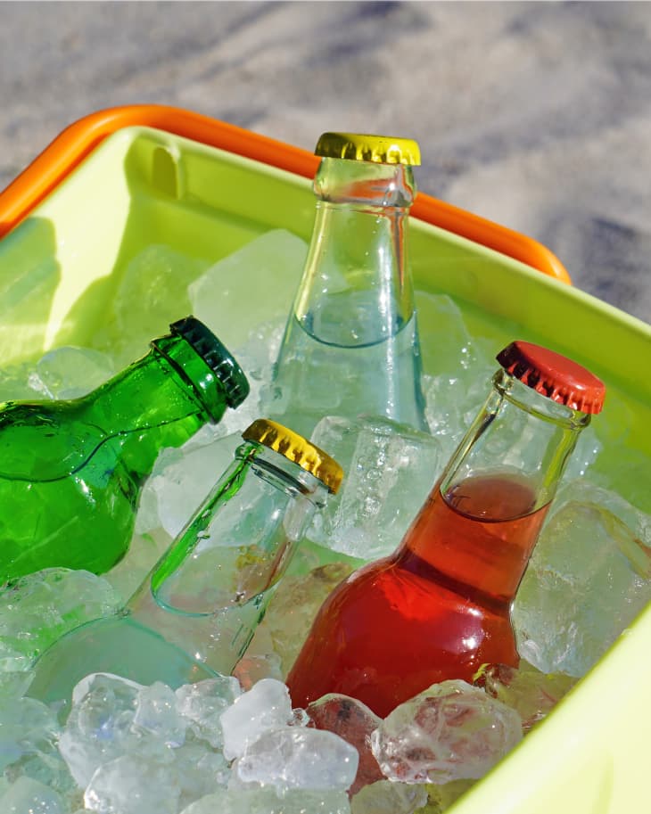 bottled drinks in lime green and orange cooler full of ice on the beach, closeup