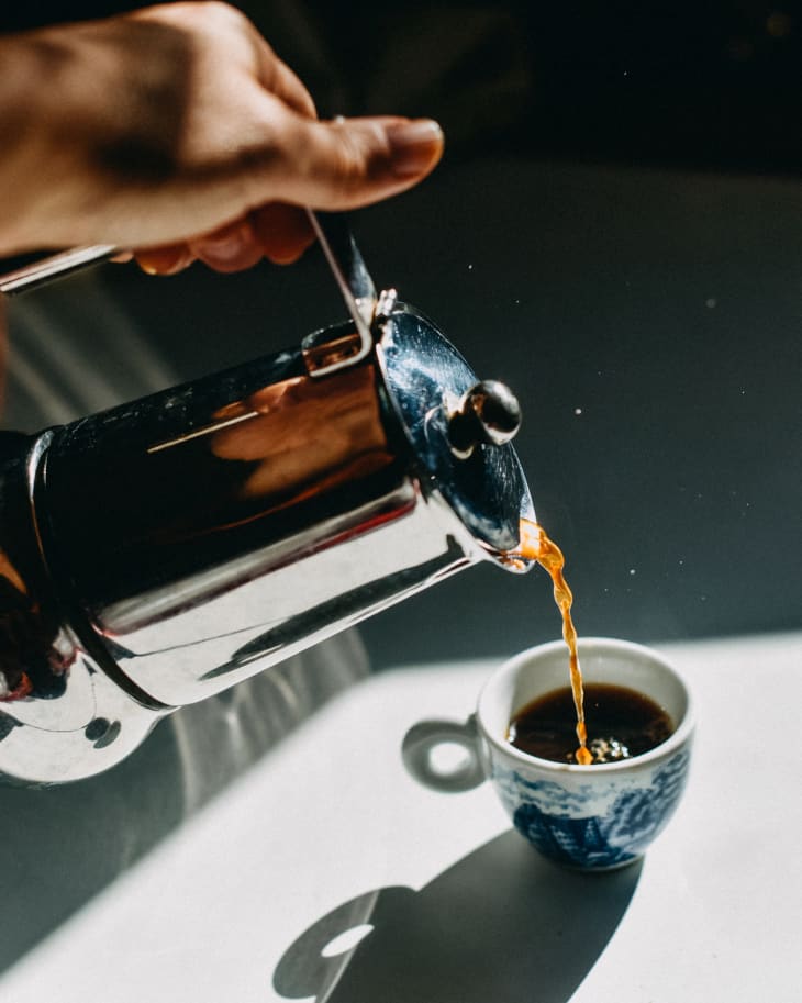 Pouring espresso coffee into an espresso cup with a mocha pot.