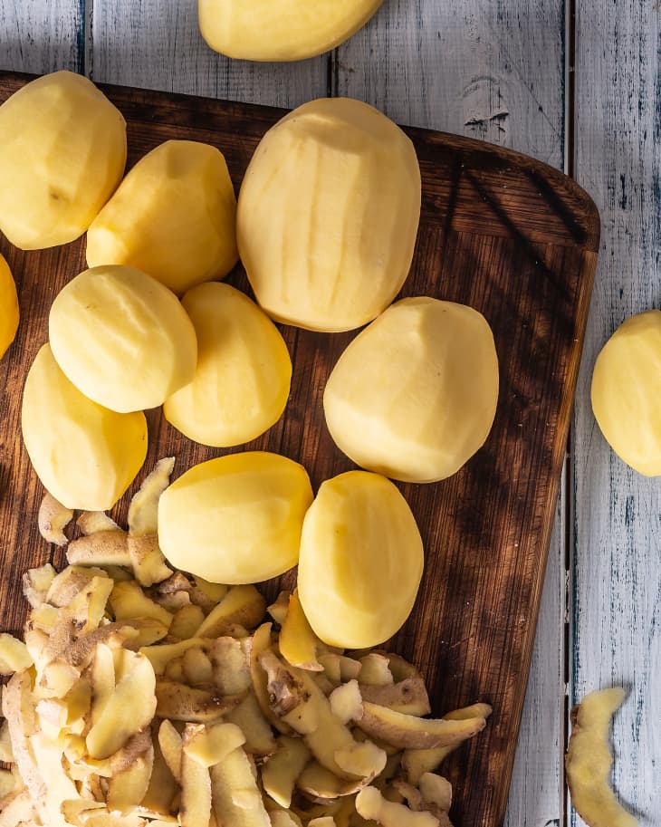 Peeled potatoes on a cutting board - top of view.