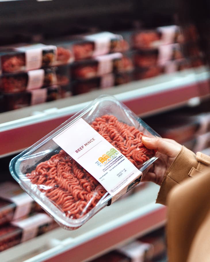 woman holding package of raw ground beef in supermarket/grocery store