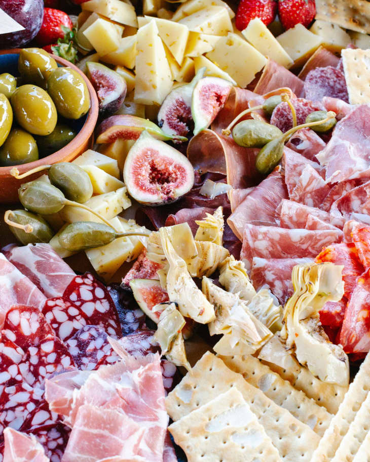 Charcuterie board with various meats, cheeses, fruit and crackers.