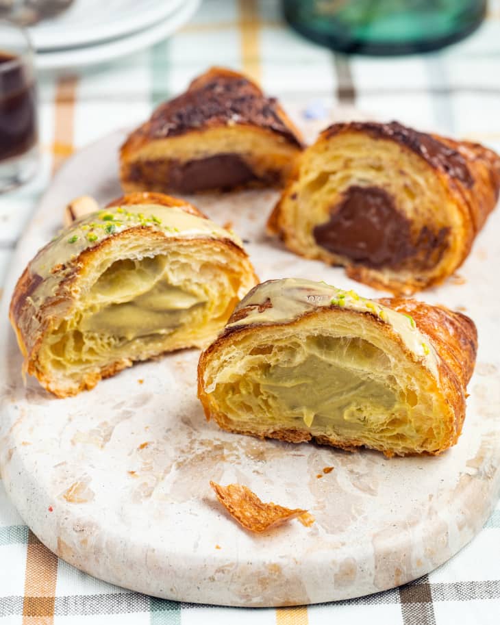 Two halved Croissants (you can see the filling) with pistachio and chocolate cream on a oblong terazzo serving board on table