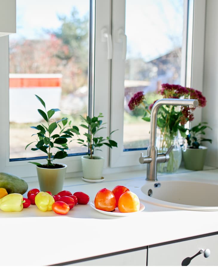 Fruits and vegetables on white counter by kitchen sink