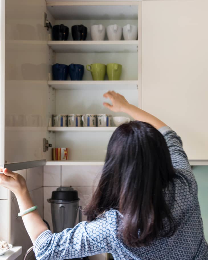 Woman taking cups out from shelf