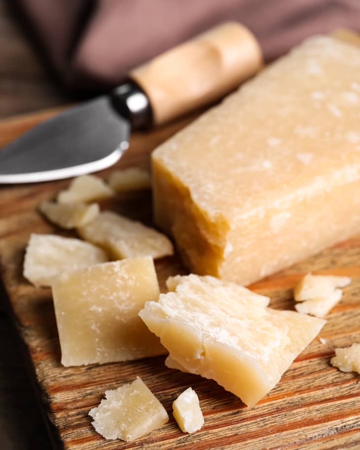 Parmesan cheese with knife on wooden board
