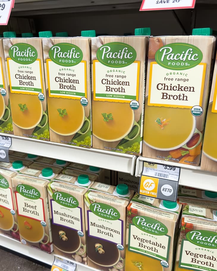 A view of several shelves dedicated to Pacific Foods stock and broth cartons, on display at a local grocery store.
