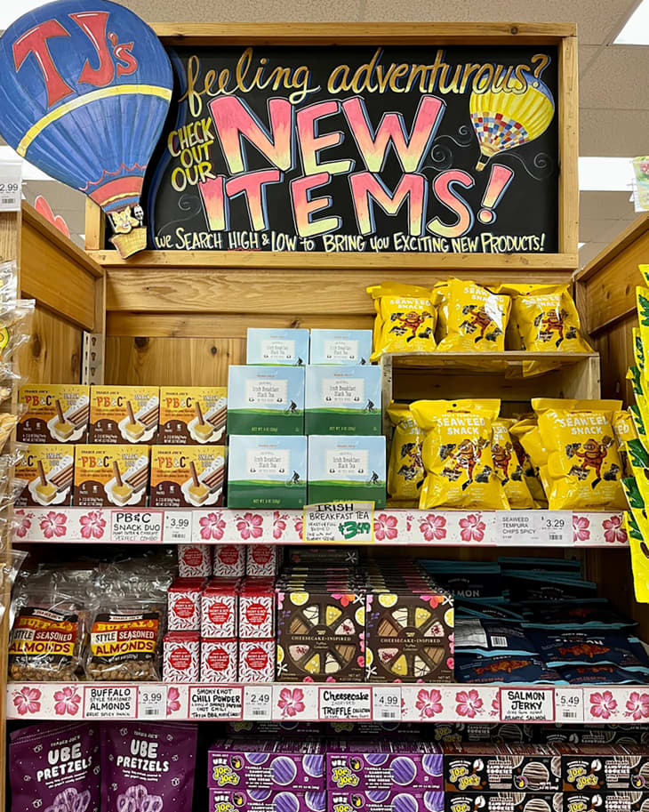 A Spring display in Trader Joe's. The sign says "Feeling adventurous? Check out our new items. We search high and low to bring you exciting new products."
