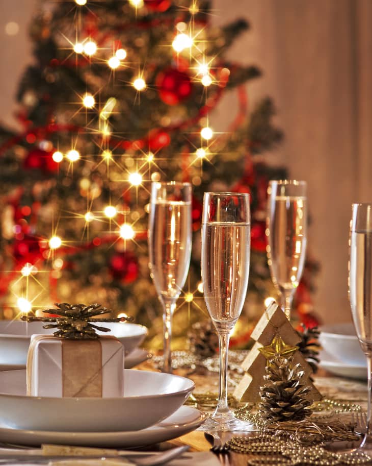 A decorated christmas dining table with champagne glasses and christmas tree in background