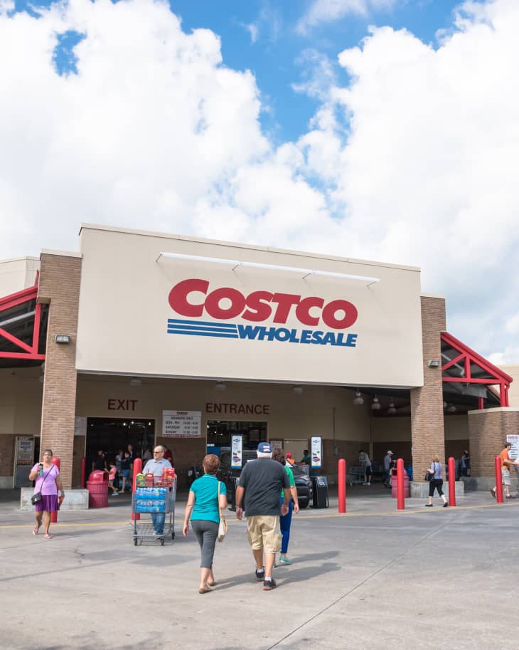 Customers walk in and exit at Costco entrance storefront. Costco Wholesale Corporation is largest membership-only warehouse club in US. It has 705 warehouses worldwide