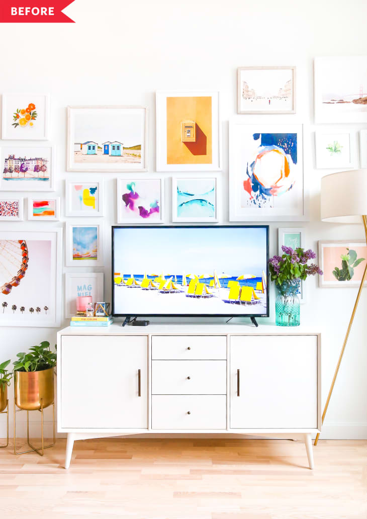 White sideboard with TV, colorful gallery wall, gold planters, and floor lamp in a bright living room.