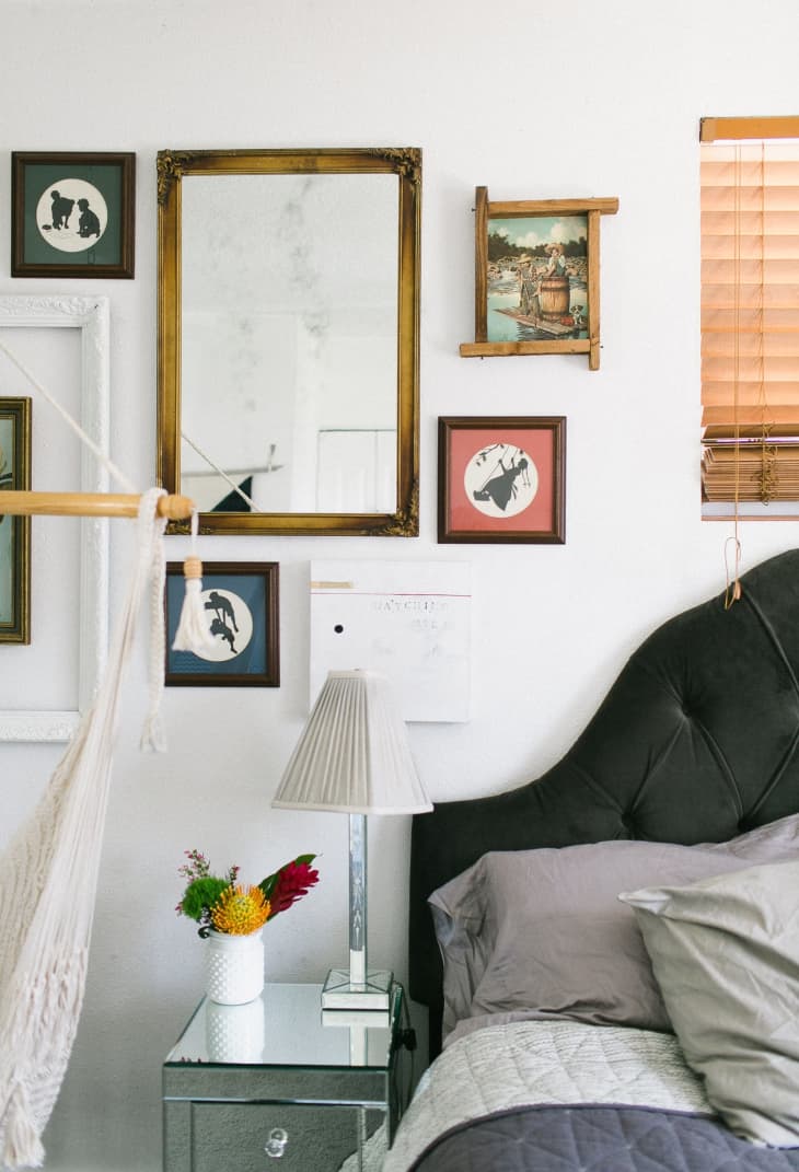 Bedroom with a tufted headboard, mirrored nightstand, lamp, and framed art on the wall.
