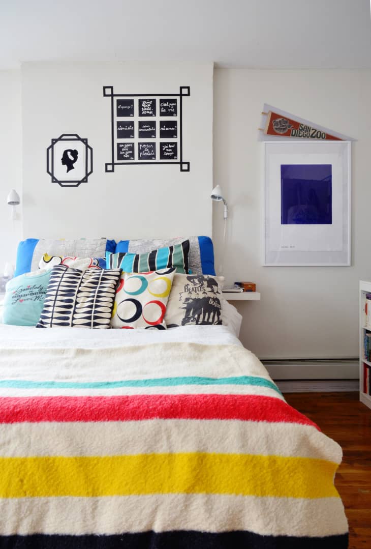Bedroom with colorful striped bedding, patterned pillows, wall art, and a San Diego Zoo pennant.
