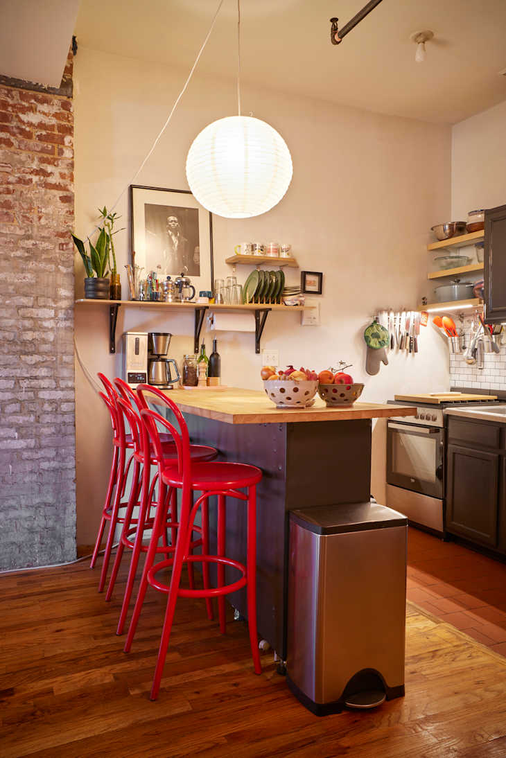 Red stools surround a dining table with stainless steel coffee maker.