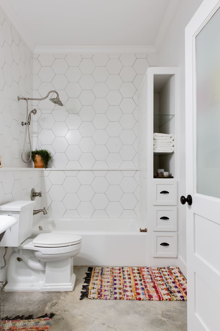 all-white bathroom features colorful rugs