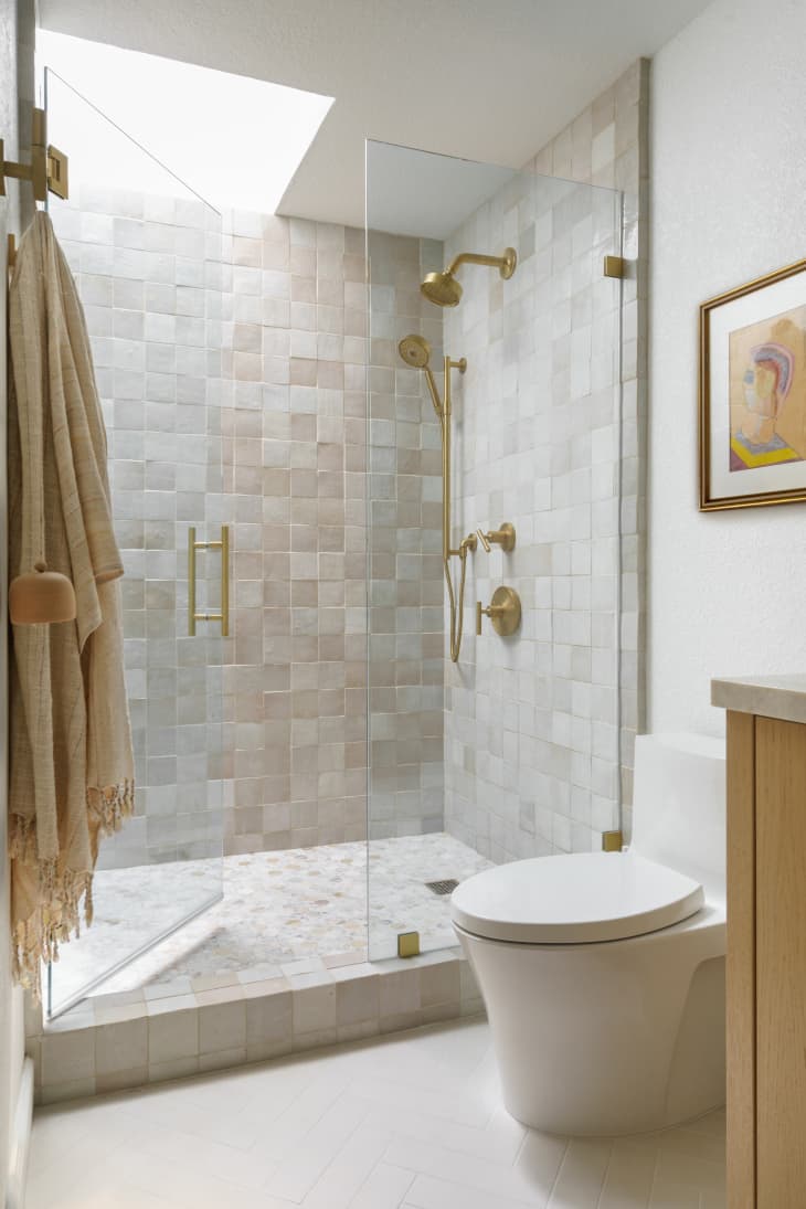 Neutral, modern bathroom with warm wood vanity and a creamy zellige tile shower with a glass door