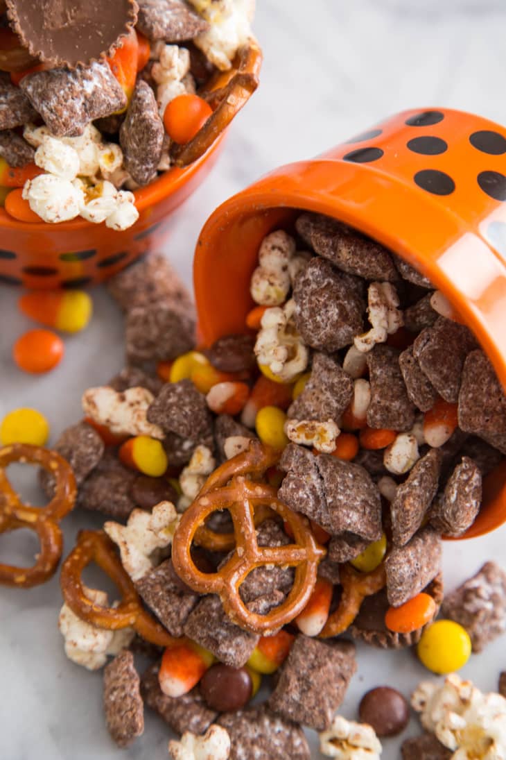 Image 4: Spilled orange bowl with Halloween mix of pretzels, popcorn, candy corn, and chocolate pieces.