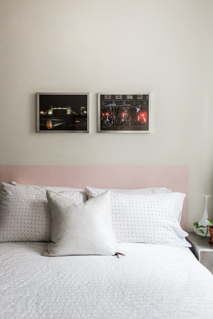Bed with white and polka dot pillows, pink headboard, and two framed photos above.