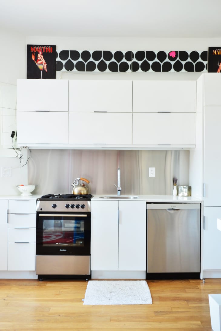 Modern kitchen with white cabinets, stainless steel appliances, and a decorative black and white wall art above.