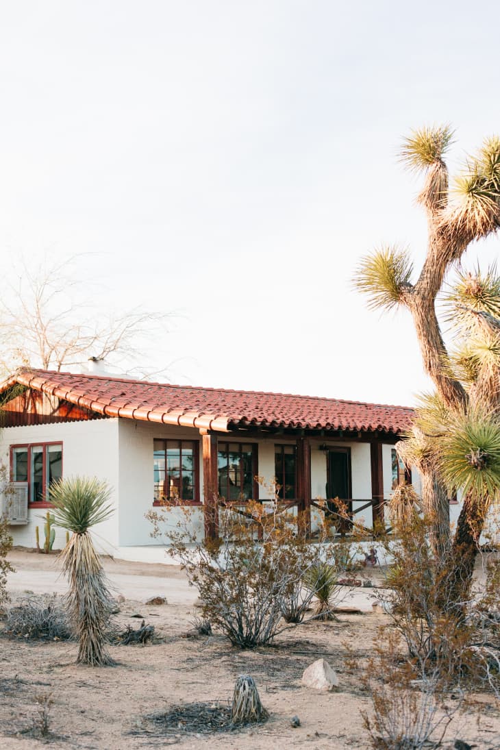 Desert house with red-tiled roof, surrounded by Joshua trees and desert shrubs.