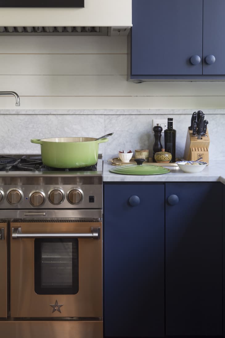 Navy blue kitchen with lime green dutch oven on a stove