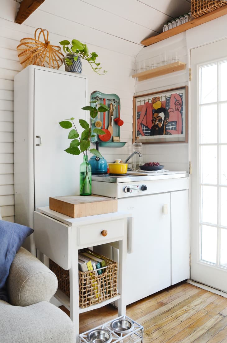 A tiny white kitchen with various shelves to hold kitchen essentials
