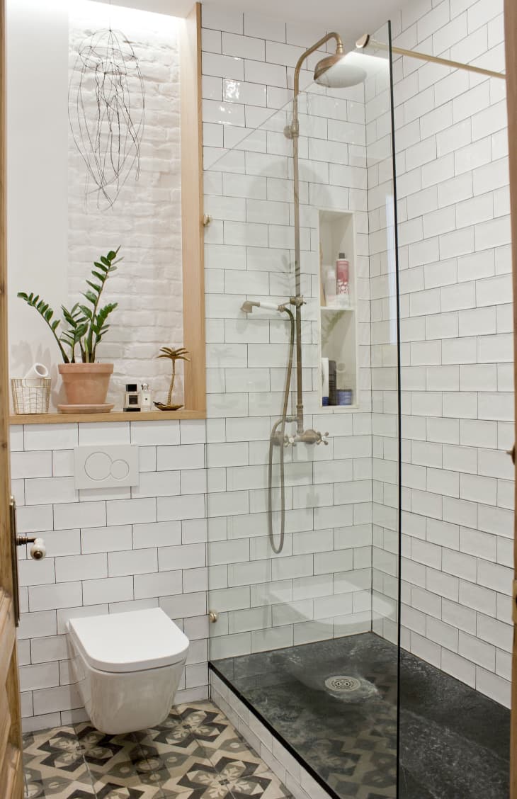 A bathroom with subway tile and a modern, wall-mounted toilet.