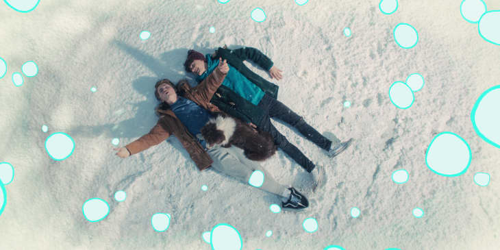 Two people lying in the snow with a dog, surrounded by animated blue bubbles.
