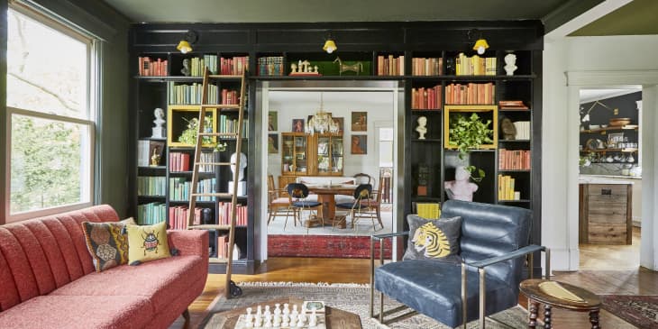 A transition between a living and dining room covered with a built-in black bookshelf