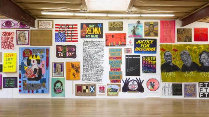 Wall of protest art featuring colorful posters and paintings advocating for justice and equality, including "Justice for Breonna."
