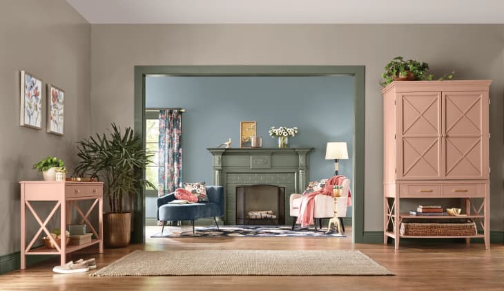 Living room with pink furniture, green fireplace, blue walls, floral curtains, and a blue velvet chair.