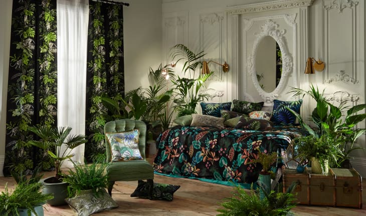 Opulent bedroom with lots of tropical plants and tropical prints.