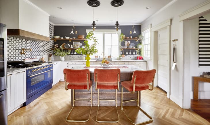 Orange bar stools and a cobalt blue oven contrast each other in this otherwise neutral kitchen
