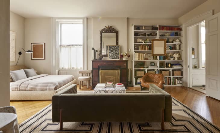 Green couch and leather lounge chair in the living area of a studio apartment.