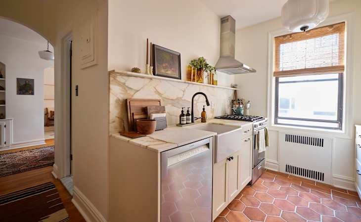 Compact kitchen featuring a marble backsplash, stainless steel appliances, and hexagonal terracotta tiles.