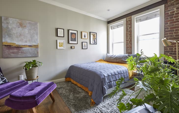 Light-filled modern bedroom in a loft apartment with brick wall and abstract art and modern colorful furniture.