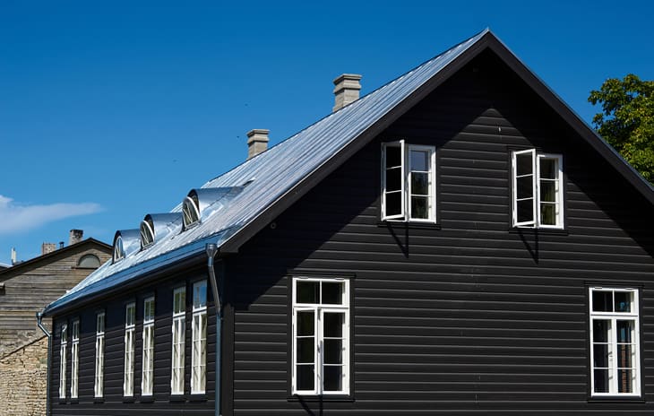 black wooden house under a gray roof against a blue sky. building architecture.