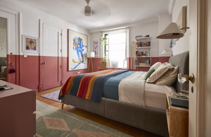 A bedroom with white and red walks with large wall art hung up.