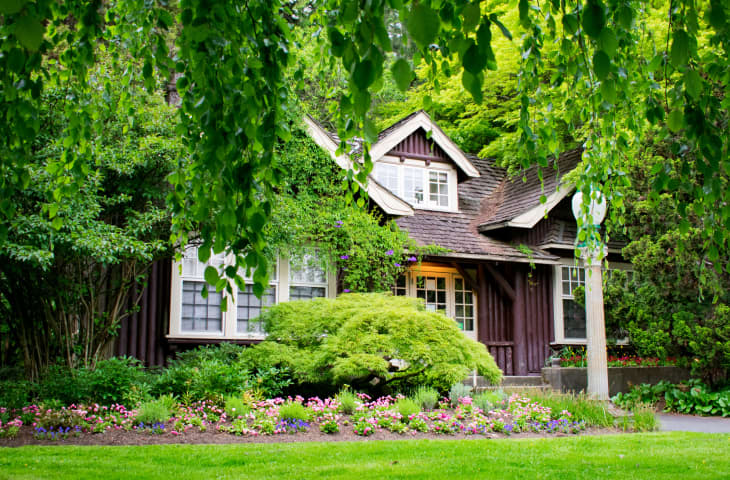 A quaint fairytale cottage, covered by lush plant life and flowers, in the Rose Garden at Stanley Park, Vancouver, British Columbia, Canada.