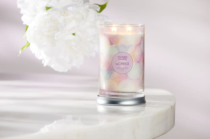 Yankee Candle "Wonder" on a marble surface with white flowers in the background.