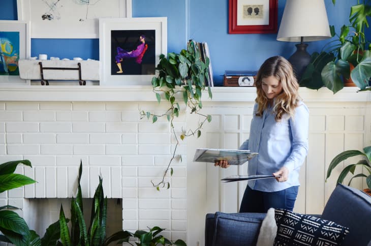 White woman sorting through stuff in her living room