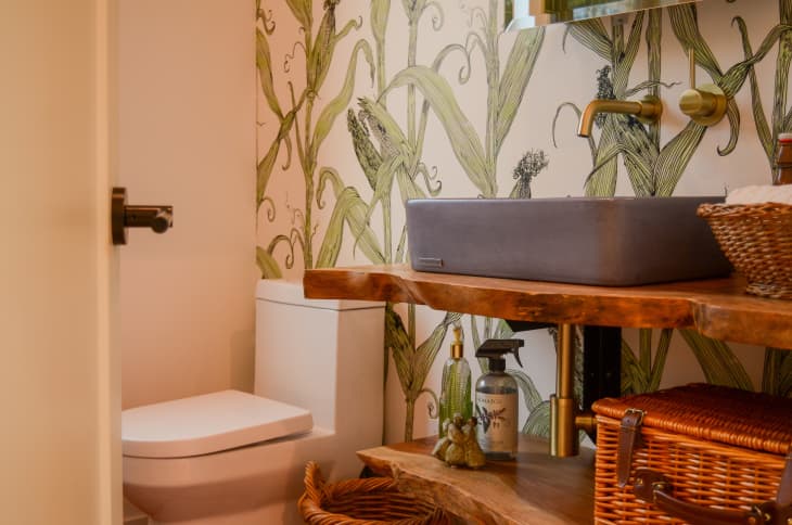 View of bathroom with natural accents and corn wallpaper.